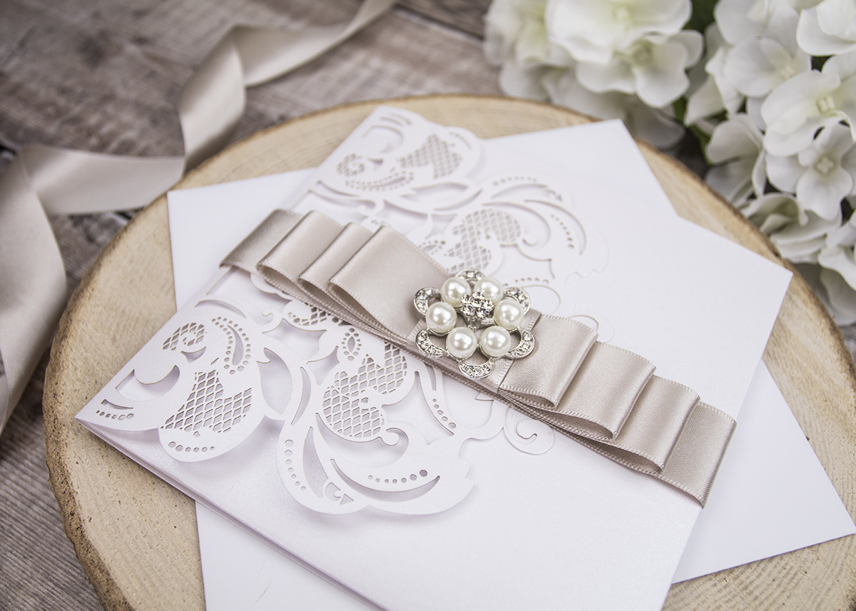 Laercut wedding invitation with ribbona nd diamante embellishment.